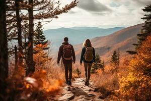 A couple hiking in the mountains with fall foliage in the blurred background photo