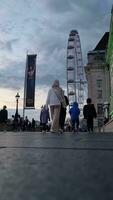 hermosa bajo ángulo imágenes de turista personas son caminando a lo largo ruta de Londres ojo a Westminster central Londres ciudad de Inglaterra genial Bretaña, imágenes estaba capturado en ago 02, 2023 durante puesta de sol. video
