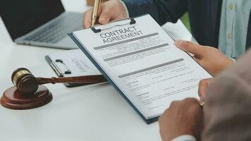 Business and lawyers discussing contract papers with brass scale on desk in office. Law, legal services, advice, justice and law concept picture with film grain effect video