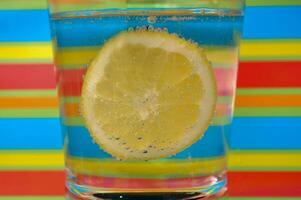 Lemonade fizzy drink in a clear glass with colorful background showing fizzy bubbles photo