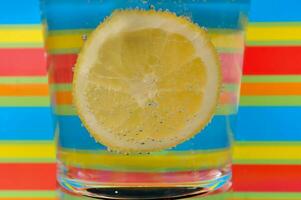 Lemonade fizzy drink in a clear glass with colorful background showing fizzy bubbles photo