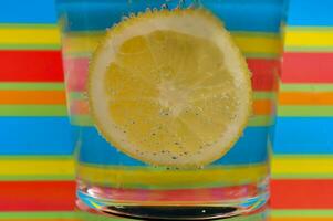 Lemonade fizzy drink in a clear glass with colorful background showing fizzy bubbles photo