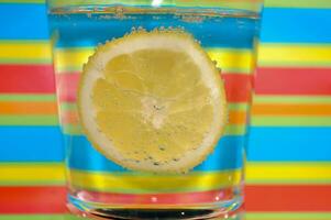 Lemonade fizzy drink in a clear glass with colorful background showing fizzy bubbles photo