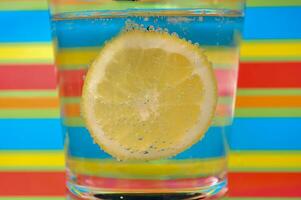 Lemonade fizzy drink in a clear glass with colorful background showing fizzy bubbles photo