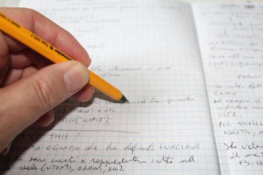 Close-up of a man's hand writing a document on a sheet of squared paper using a fountain pen photo