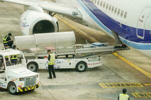 Bangkok, Thailand, 2018 - New gen airline staff using cargo cart delivery baggage to loader cart loading luggage to the airplane. photo