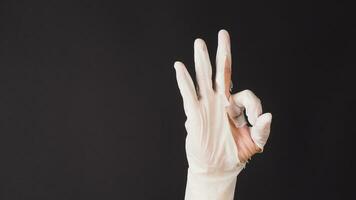 Ok hand sign and wear latex glove on black background. photo