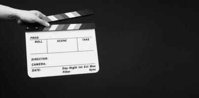 Hand is holding clapper board or movie slate.It is used in video production and film industry on black background. photo