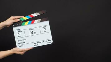 Hand is holding clapper board or movie slate with write in number on black background. photo