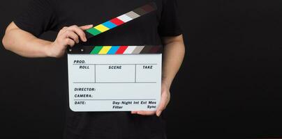 Hand is holding clapper board or movie slate.It is used in video production and film industry on black background. photo