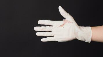 Hand Wearing torn latex glove or torn rubber gloves on black background. photo