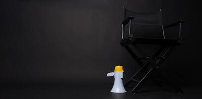 negro director silla y megáfono en negro fondo negro. foto