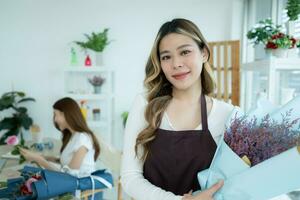 beautiful asian woman florist making bouquet in flower shop photo