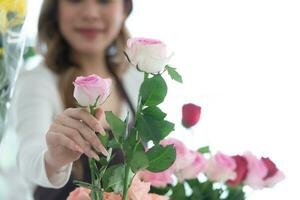 joven mujer florista oliendo un rojo Rosa en el flor tienda foto