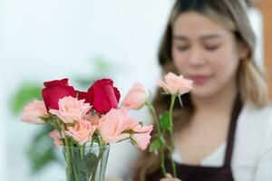 hermosa asiático mujer florista participación ramo de flores de rosas en flor tienda. foto