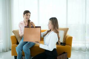 el recepcionista entrega el bienes ese el cliente tiene ya comprado a asiático mujer en el sofá con compras pantalones foto