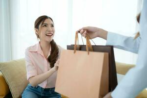 el recepcionista entrega el bienes ese el cliente tiene ya comprado a asiático mujer en el sofá con compras pantalones foto