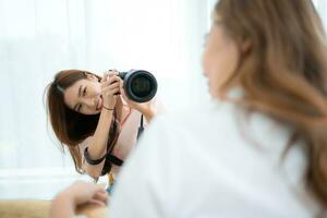 Beautiful asian woman photographer taking picture with professional camera at home photo