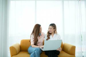 LGBT couple sitting on sofa and using laptop computer at home. photo