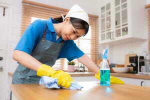 Young woman cleaning the table in the kitchen. Housekeeping and housekeeping concept. photo