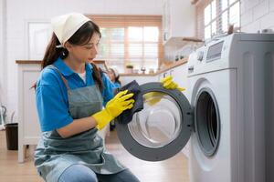 Asian young woman cleaning the washing machine in the kitchen. housework concept photo