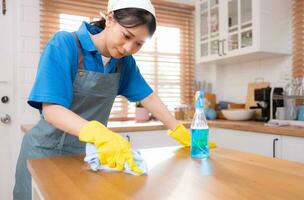 Young woman cleaning the table in the kitchen. Housekeeping and housekeeping concept. photo