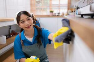 Asian young woman cleaning the countertops cupboard in the kitchen. housework concept photo