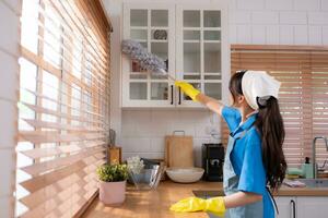 Asian young woman cleaning window in the kitchen. housework concept photo