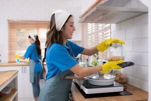 Portrait of young asian woman cleaning in the kitchen at home photo