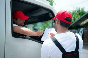 entrega hombre en rojo gorra y uniforme entregando paquete o empaquetar a recipiente - mensajero Servicio concepto foto