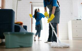 Two young women in uniform are cleaning the living room at home. photo