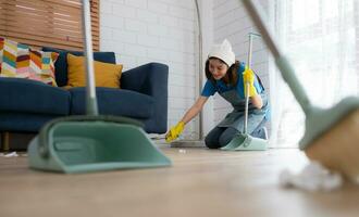 Cleaning service. Dark-haired woman wearing a white hat and yellow gloves cleaning the floor photo