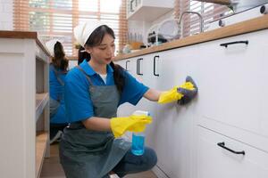 Asian young woman cleaning the countertops cupboard in the kitchen. housework concept photo