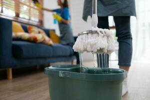 Close-up of mop and bucket with cleaning products in living room photo