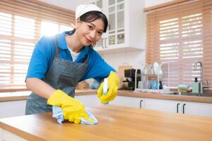 Young woman cleaning the table in the kitchen. Housekeeping and housekeeping concept. photo