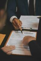 Business and lawyers discussing contract papers with brass scale on desk in office. Law, legal services, advice, justice and law concept picture with film grain effect photo