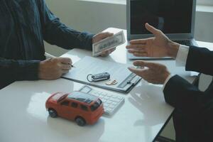 Closeup asian male people car salesman or sales manager offers to sell a car and explains and reads the terms of signing a car contract and insurance. photo