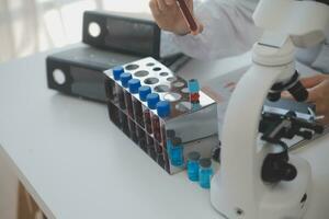 Professional lab. Amazing longhaired medical worker wearing uniform while using microscope during research photo