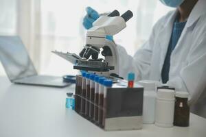 Professional lab. Amazing longhaired medical worker wearing uniform while using microscope during research photo