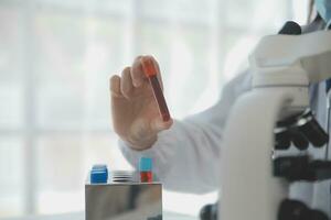 Professional lab. Amazing longhaired medical worker wearing uniform while using microscope during research photo