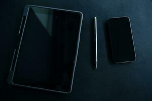 Open laptop with digital tablet and white smartphone. All with isolated screen on old wooden desk. photo