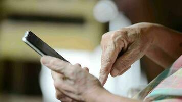 detailopname schot van een gerimpeld hand- van een ouderen vrouw wie is Aan een mobiel baan video