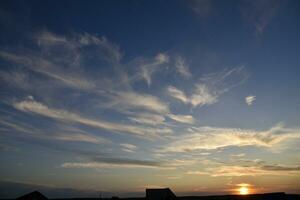 hermosa verano puesta de sol noche. azul amarillo nubes de el ajuste Dom. puesta de sol horizonte. foto