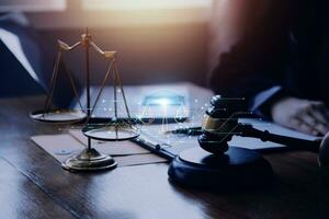 Justice and law concept.Male judge in a courtroom with the gavel, working with, computer and docking keyboard, eyeglasses, on table in morning light photo