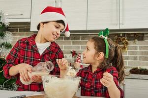 Beautiful European children enjoying time together, having fun while kneading dough, cooking cookies and bakeries, helping their mother at home kitchen. Christmas and happy childhood concept photo