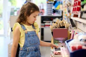 Adorable child girl, choosing school stationery in office supply store. Back to school on new semester of academic year photo