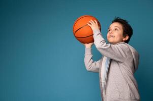 Adorable boy playing basketball on blue background with space for text photo