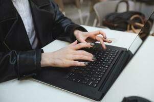 de cerca de mujer manos mecanografía texto en ordenador portátil teclado. negocio, Lanza libre, redacción publicitaria, asistente remoto trabajar, Internet aprendiendo, en línea compras concepto en abierto aire fuera de cafetería foto