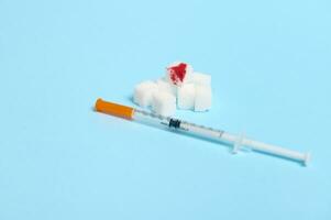Refined pure white sugar cubes with blood drop and insulin syringes lying on blue background with copy space for World Diabetes Day medical advertisement. World diabetes awareness day, 14 November photo