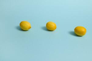 Bright yellow lemons on blue pastel background. Minimalistic food composition with copy space for advertisement photo